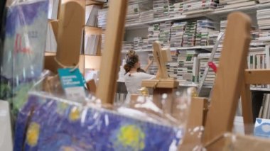 09.05.2021 - Moskova, Rusya - bir sanat mağazasındaki kadın sanatçı ürünleri seçiyor. Modern kadın süpermarketten alışveriş yapıyor..