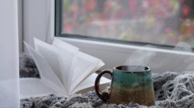 Videoyu kapat. Yağmurlu bir arkaplanda buharlı kahve fincanı. Sıcak atmosfer, soğuk havada. Yağmurlu gün havası.