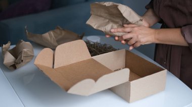 Kadın içeride paket açıyor. Kadın, evdeki oturma odasında karton kutuları açıp açıyor. iyi dağıtım servisi.