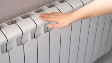 Kadınlar radyatöre dokunur. Sıcak radyatör, ısıtma mevsimi konsepti