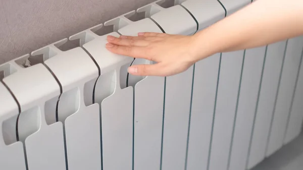 La mano de las mujeres toca el radiador. radiador caliente, concepto de temporada de calefacción — Foto de Stock