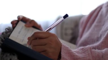 Sıcak örgü süveter giyen tanınmayan bir kadın yeni yıl için planlar ve görevler yazar..