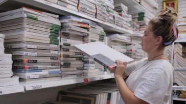 09.05.2021 - Moskova, Rusya - bir sanat mağazasındaki kadın sanatçı ürünleri seçiyor. Modern kadın süpermarketten alışveriş yapıyor..