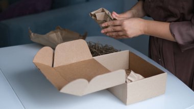 Kadın içeride paket açıyor. Kadın, evdeki oturma odasında karton kutuları açıp açıyor. iyi dağıtım servisi.