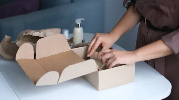 Mujer abriendo el paquete en el interior. mujer abriendo y desempacando paquete de caja de cartón en la sala de estar en casa. buen servicio de entrega. —  Fotos de Stock