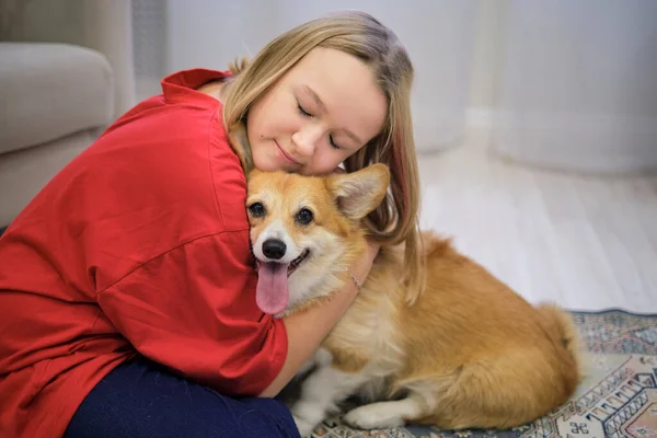 Menina bonito abraçando cão corgi com olhos de amor fechado, sorrindo. Amante de cão com animal doméstico — Fotografia de Stock