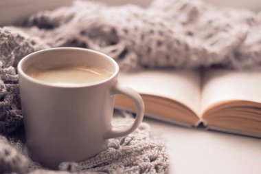 Bir fincan kahve ve bir kitapla rahat bir ev. Hygge tarzı. Tahta tahtada sıcak atkı ile sarılmış siyah kahve bardağı. Üst görünüm, vintage tarzı, Natürmort.