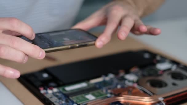 Nierozpoznawalny inżynier robi zdjęcia płyty głównej laptopa na smartfonie. Remont elektroniczny, biznes, koncepcja zawodu — Wideo stockowe