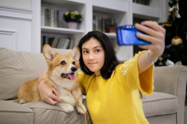 Genç kız evde köpeğiyle selfie çekiyor. Evcil hayvanlı köpek sever. Modern teknoloji, insanlar ve hayvanlar konsepti.