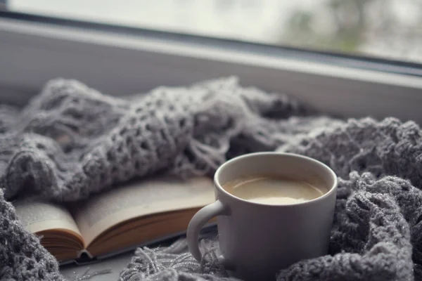 Уютный дом с чашкой кофе и книгой. В стиле Хигге. Кружка черного кофе, завернутая в теплый шарф на деревянной доске. Вид сверху, винтажный стиль, натюрморт . — стоковое фото