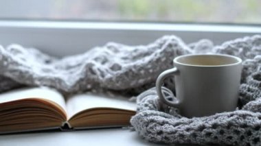 Bir fincan kahve ve bir kitapla rahat bir ev. Hygge tarzı. Tahta tahtada sıcak atkı ile sarılmış siyah kahve bardağı. Üst görünüm, vintage tarzı, Natürmort.