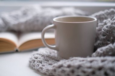 Bir fincan kahve ve bir kitapla rahat bir ev. Hygge tarzı. Tahta tahtada sıcak atkı ile sarılmış siyah kahve bardağı. Üst görünüm, vintage tarzı, Natürmort.