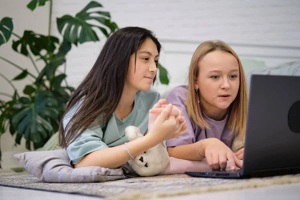 Két tinédzser lány fekszik a hálószoba padlóján, és filmet néznek egy laptopon. Barátság fogalma — Stock Fotó