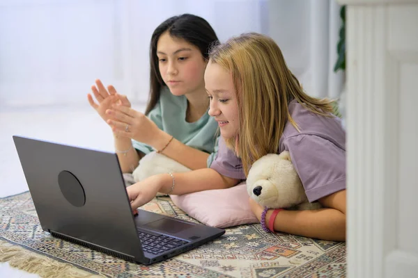 Két tinédzser lány fekszik a hálószoba padlóján, és filmet néznek egy laptopon. Barátság fogalma — Stock Fotó