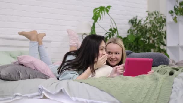 Duas meninas adolescentes sentam-se no laptop e olham para o monitor conversando com amigos através de vídeo chat. — Vídeo de Stock