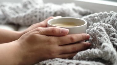 Bir fincan kahve ve bir kitapla rahat bir ev. Hygge tarzı. Tahta tahtada sıcak atkı ile sarılmış siyah kahve bardağı. Üst görünüm, vintage tarzı, Natürmort.