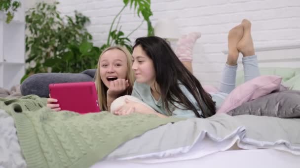 Twee tiener meisjes zitten op de laptop en kijk naar de monitor chatten met vrienden via video chat. — Stockvideo