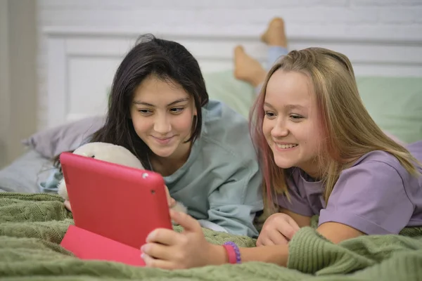Két tini lány ül a laptopnál, és nézi a monitort, ahogy beszélgetnek a barátaikkal videó chat közben.. — Stock Fotó
