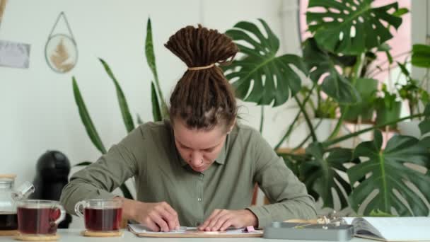 Žena opravuje skleněné talíře. Obrázek sušených květin. Mistrovská třída na vytváření rámu s herbářem v tiffany technice v barevném skle. — Stock video