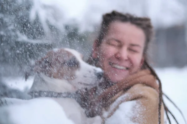 Расслабься, женщина обнимает собаку. Снегопад. Играю с собакой. Женщина выгуливает собаку зимой и исследует вместе снег в игривом настроении. — стоковое фото