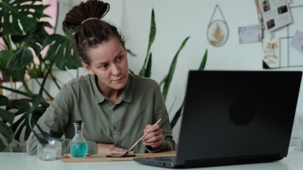 Frau fixiert Glasplatten. Ein Bild von getrockneten Blumen. Meisterkurs zur Gestaltung von Rahmen mit Herbarium in Tiffany-Technik in Glasmalerei. — Stockvideo