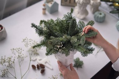 Kadın bir Noel düzenlemesi hazırlıyor. Eller yakın çekim. Yeni yıl kutlaması. Çiçekçi. Masa süslemeleri, çiçek kompozisyonu. yumuşak odak