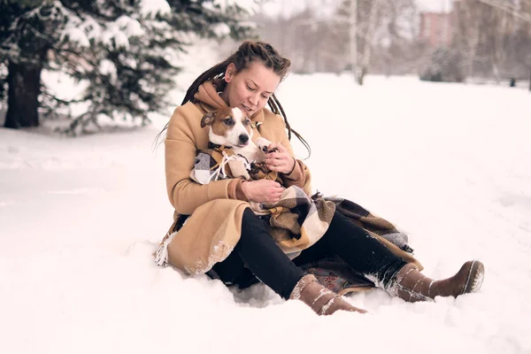 Игривая женщина с собакой. стильная хипстерская женщина обнимает и улыбается милый щенок в снежном холодном зимнем парке. моменты настоящего счастья. — стоковое фото