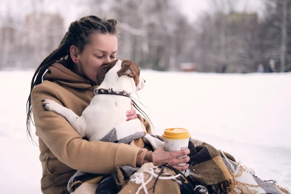 Игривая женщина с собакой. стильная хипстерская женщина обнимает и улыбается милый щенок в снежном холодном зимнем парке. моменты настоящего счастья. — стоковое фото