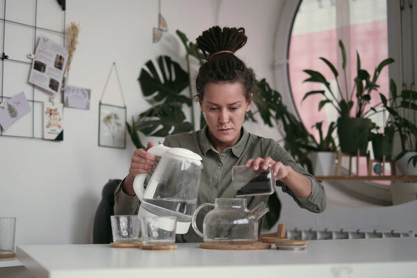 woman in a linen shirt pours tea into two transparent cups. hospitality concept, hostess treats guest to tea