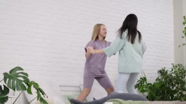 Evdeki yatakta dans eden genç kızlar. Çok uluslu iki genç kız birlikte zaman geçiriyorlar, pijama partisi. En iyi arkadaşlar selfie çeker..