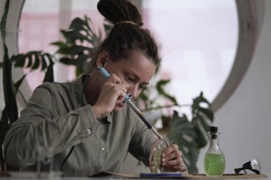 Lekeli cam imalatçısı renkli hatıralarla çalışır. Kadın elleri lehimlenmiş camları lehimliyor, vitray yapmayı öğreniyor, el işi bitiriyor, silah lehimliyor.