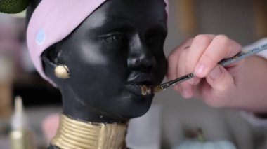 Kadın bir vazoyu alçı büstü şeklinde dekore ediyor. Afro-Amerikalı kadın baskını. Kadın kafası şeklinde saksılar, çiçekler için saksılar. yumuşak odak