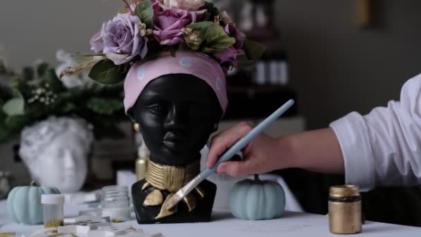 Mujer decora un jarrón en forma de busto de yeso. Busto de mujer afroamericana. ollas para flores en forma de cabeza de mujer. enfoque suave — Vídeos de Stock