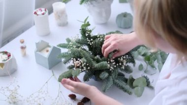 Kadın bir Noel masa süslemesi dekore etmiş. Eller yakın çekim. Dekoratif süsler konusunda yüksek lisans. Noel dekorunu kendi elleriyle yaptılar. Çiçekçi. Köknar dallarının Noel kompozisyonu.