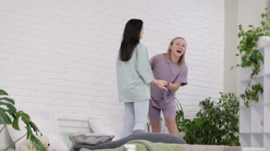 Evdeki yatakta dans eden genç kızlar. Çok uluslu iki genç kız birlikte zaman geçiriyorlar, pijama partisi. En iyi arkadaşlar selfie çeker..