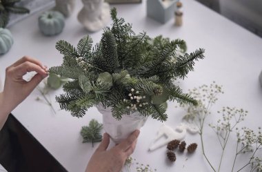 Atölye Ustası el yapımı bir Noel masa süsü yaptı. Eller yakın çekim. Noel dekorunu kendi ellerinle yaptın. Masa süslemeleri, çiçek kompozisyonu.