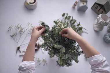 Atölye Ustası el yapımı bir Noel masa süsü yaptı. Eller yakın çekim. Noel dekorunu kendi ellerinle yaptın. Masa süslemeleri, çiçek kompozisyonu.