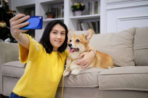 Девочка-подросток делает селфи со своей собакой дома. Любитель собак с домашним животным. Современные технологии, люди и животные. — стоковое фото