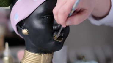 Kadın bir vazoyu alçı büstü şeklinde dekore ediyor. Afro-Amerikalı kadın baskını. Kadın kafası şeklinde saksılar, çiçekler için saksılar. yumuşak odak