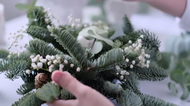 Kobieta udekorowała świąteczny stół. Ręce do góry. Mistrzowskie zajęcia z dekoracji dekoracyjnych. Wystrój świąteczny własnymi rękami. Kwiaciarnia. Świąteczny skład gałązek jodłowych. — Wideo stockowe