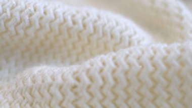 Hareket videosunu kapatıyoruz. Tekstil soyut arka planı. Kıyafet endüstrisi konsepti. Dalgalı temiz malzeme. Beyaz ipliklerle örülmüş kumaş iplikleri. Örgü kumaş iplikler makro.