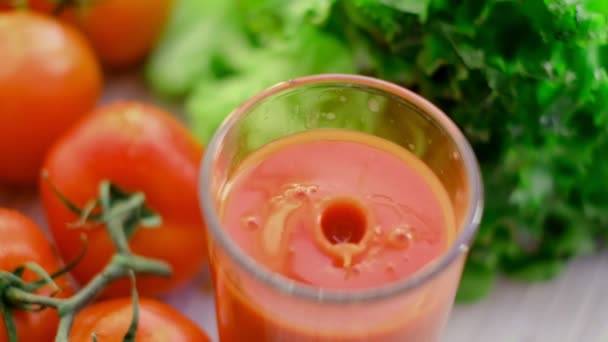 Bir bardak meyve suyuna damlayan domates suyu damlaları. Arka planda domates filizi olan domates suyu. Domates suyu bardağa dökülür.. — Stok video