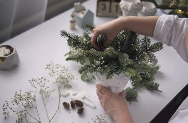 Atölye Ustası el yapımı bir Noel masa süsü yaptı. Eller yakın çekim. Noel dekorunu kendi ellerinle yaptın. Masa süslemeleri, çiçek kompozisyonu.