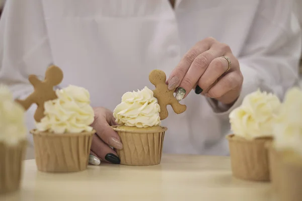 Konditor drückt eine weiße Sahne in Form von Rosenblüten aus. Prozess der Dekoration von Cupcakes mit weißer Schlagsahne. Dekorieren einer weißen Torte mit Sahne aus dem Gebäckbeutel. — Stockfoto