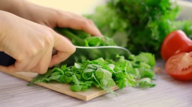 Kadın elleri bir demet taze kereviz dilimlemek için bıçak kullanıyor. Yiyecek taze kereviz sapları soyuluyor. Mutfak yemekleri hazır..