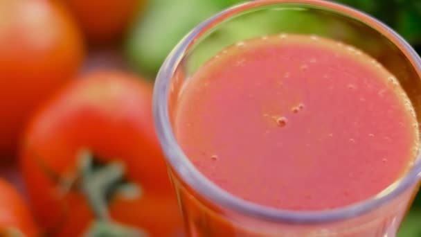 Tomato juice with sprig of tomatoes on background. Tomato juice is poured into a glass. slow motion — Stock Video
