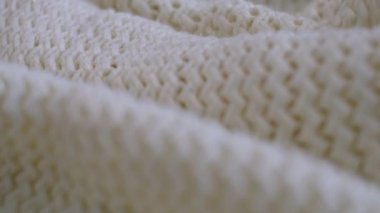 Hareket videosunu kapatıyoruz. Tekstil soyut arka planı. Kıyafet endüstrisi konsepti. Dalgalı temiz malzeme. Beyaz ipliklerle örülmüş kumaş iplikleri. Örgü kumaş iplikler makro.