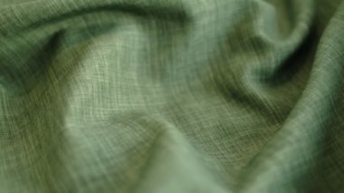 Hareket videosunu kapatıyoruz. Yeşil keten tekstil soyut arka plan. Kıyafet endüstrisi konsepti. Dalgalı malzeme. Kadife kumaş iplikler makro. Yan görüş. Yakın çekim stok görüntüleri