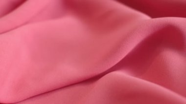 Hareket videosunu kapatıyoruz. Pembe tekstil soyut arka planı. Kıyafet endüstrisi konsepti. Dalgalı malzeme. Kadife kumaş iplikler makro. Yan görüş. Yakın çekim stok görüntüleri