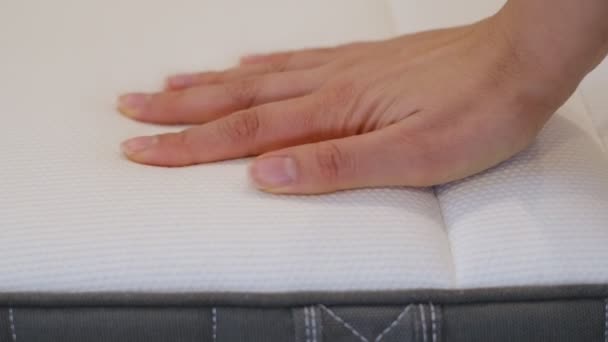 Woman is choosing new mattress for good sleeping. Hand of woman is testing mattress quality. Checking softness. Choice of the best type and quality. Side view. Closeup. — Vídeo de Stock